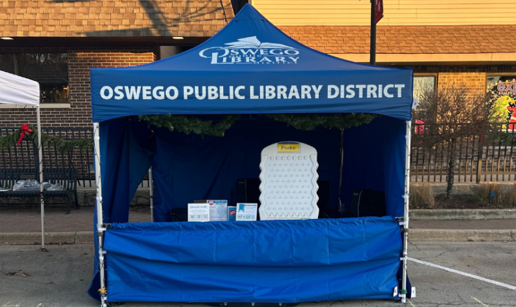 Image of blue library Outreach tent on street in front of downtown Oswego buildings.