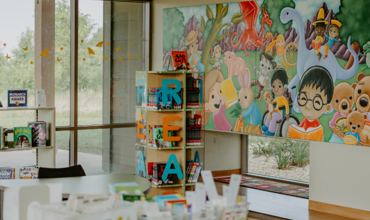 Image of library youth area showing a colorful mural a small bookcase with large letters that spell out the word READ.